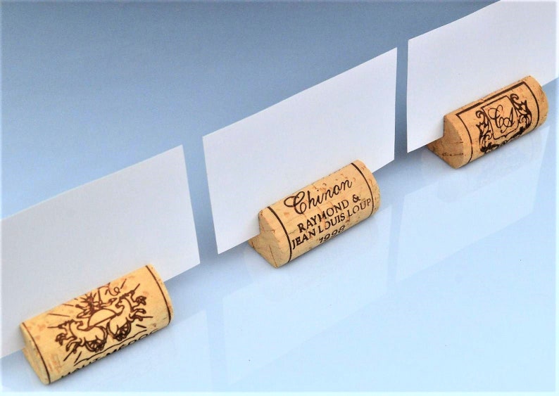 Cork card holders, perfect for wine themed weddings, rustic weddings, parties and anniversaries, these are from different vineyards and labels. 100% Natural High Quality cork with perfect cuts. On a white table with decorative flowers.