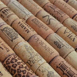 May include: Close-up of a collection of wine corks, each with unique printed designs and text. The corks are arranged diagonally, showcasing a variety of brands and styles, with a natural, textured appearance.