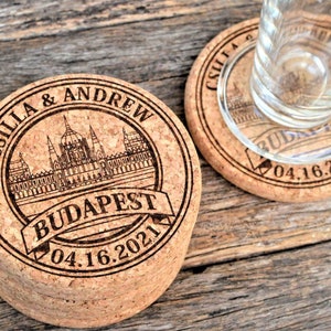 Personalized engraved cork coasters Budapest design, used for rustic wedding decorations, wedding favors and parties. They are made of high quality natural cork. On a wooden table. An excellent gift for guests and loved ones.