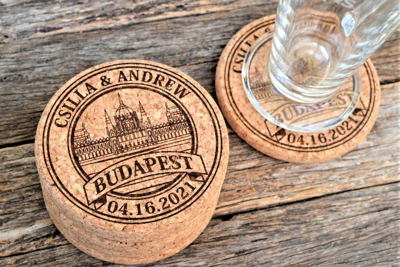 Personalized engraved cork coasters Budapest design, used for rustic wedding decorations, wedding favors and parties. They are made of high quality natural cork. On a wooden table. An excellent gift for guests and loved ones.