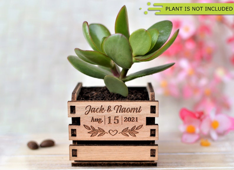 Engraved personalized mini pots, used for wedding favors, rustic style wedding decorations and your home. It is made of wood, with a succulent plant on a wooden table decorated with flowers. An excellent gift for guests and all your loved ones.