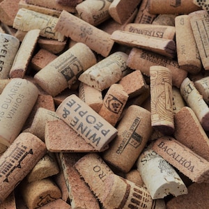 Puede incluir: Primer plano de un montón de corchos de vino usados. Los corchos, en varios tonos de marrón y beige, tienen textos y diseños impresos. Algunos corchos muestran las palabras "Wine & People" y "Luis Duarte Vinhos".