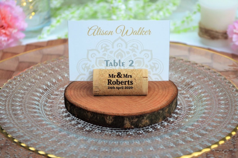 Personalized engraved horizontal wine cork, number 19 design, used for rustic wedding place cards, wedding place holder, parties and table decoration. on a wooden base with decorative flowers. Gift for guests, beautiful decoration for weddings.