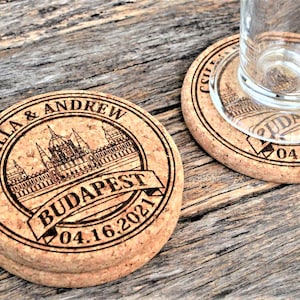 Personalized engraved cork coasters Budapest design, used for rustic wedding decorations, wedding favors and parties. They are made of high quality natural cork. On a wooden table. An excellent gift for guests and loved ones.