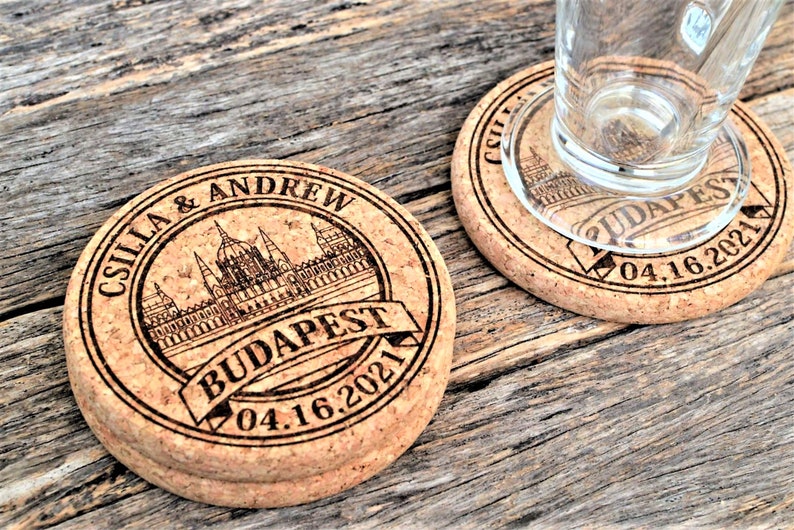 Personalized engraved cork coasters Budapest design, used for rustic wedding decorations, wedding favors and parties. They are made of high quality natural cork. On a wooden table. An excellent gift for guests and loved ones.