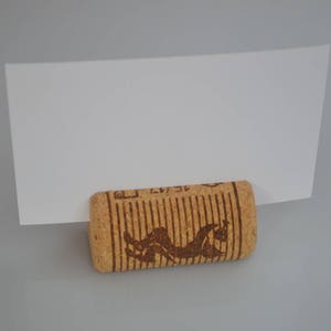 Cork card holder from different vineyards. Used for rustic wedding cards, wedding booths, anniversaries, parties and table decorations. on a wooden base with decorative flowers. for wedding favors