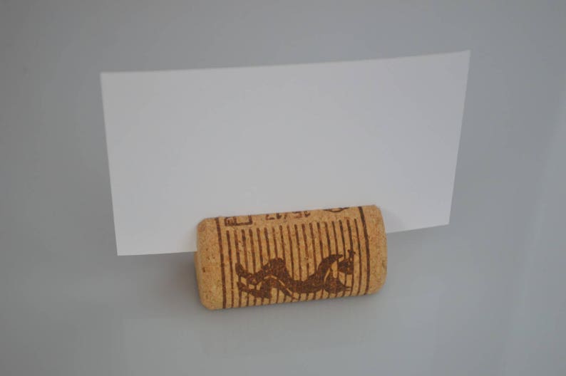 Cork card holder from different vineyards. Used for rustic wedding cards, wedding booths, anniversaries, parties and table decorations. on a wooden base with decorative flowers. for wedding favors