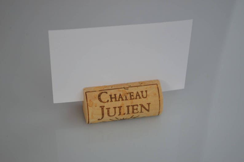 Cork card holder from different vineyards. Used for rustic wedding cards, wedding booths, anniversaries, parties and table decorations. on a wooden base with decorative flowers. for wedding favors