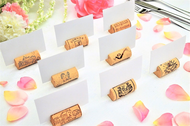 Cork card holder from different vineyards. Used for rustic wedding cards, wedding booths, anniversaries, parties and table decorations. on a wooden base with decorative flowers. for wedding favors