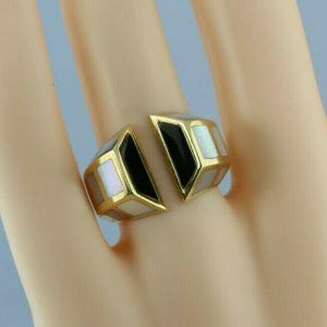 May include: A gold ring with black and white inlay. The ring is split into two pieces, each with a geometric design.