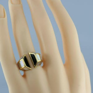 May include: A gold ring with black and white inlay. The ring is open on one side and has a geometric design.
