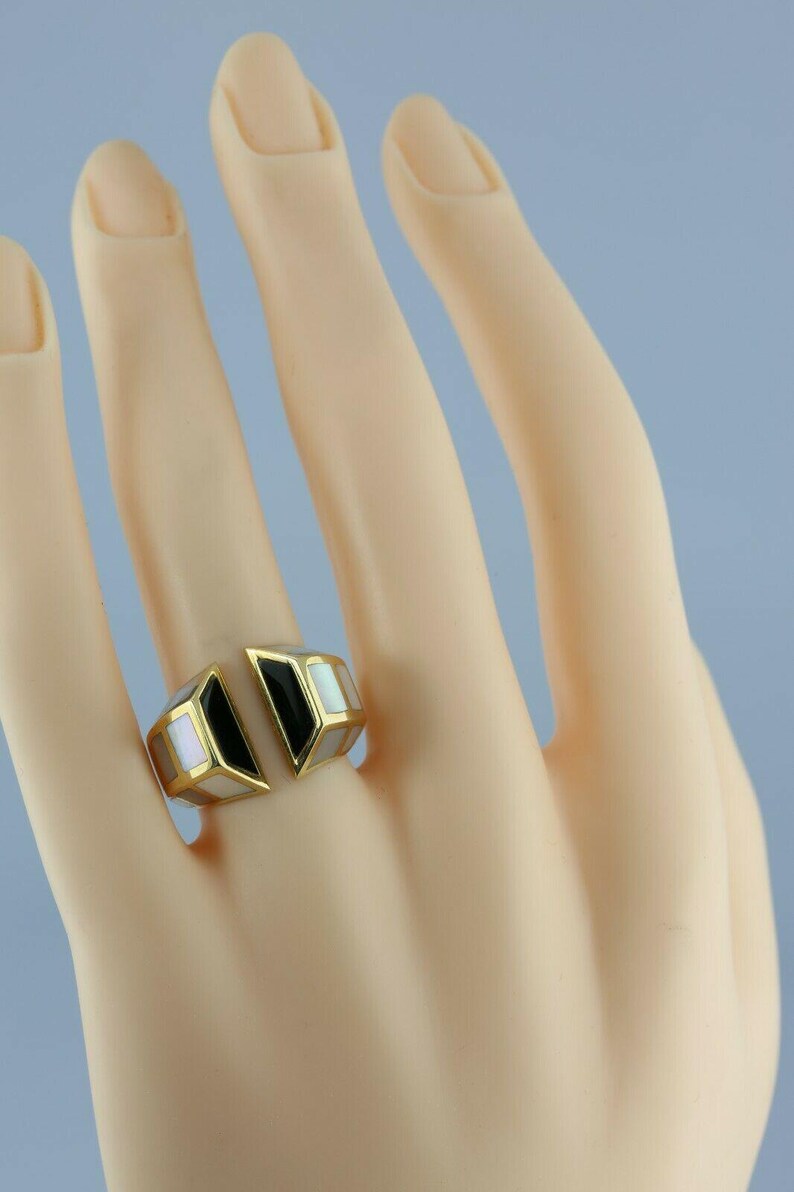May include: A gold ring with black and white inlay. The ring is open on one side and has a geometric design.