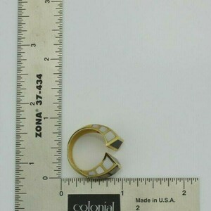 May include: A gold ring with black and white inlay. The ring is open on one side and has a geometric design.
