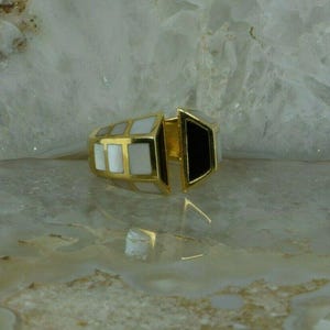 May include: A gold ring with a white and black geometric design. The ring is made of two pieces that fit together.