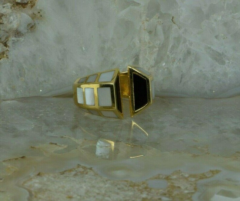 May include: A gold ring with a white and black geometric design. The ring is made of two pieces that fit together.