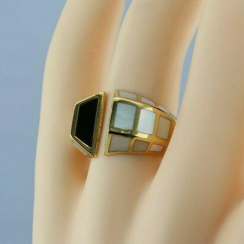 May include: A gold ring with a black and white geometric design. The ring is made of gold and has a black stone on one side and a white stone on the other.