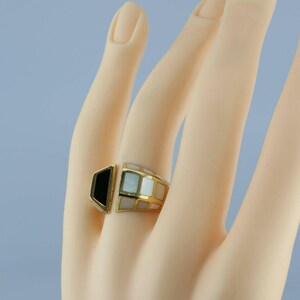 May include: A gold ring with black and white inlay. The ring is geometric in shape and has a unique design.