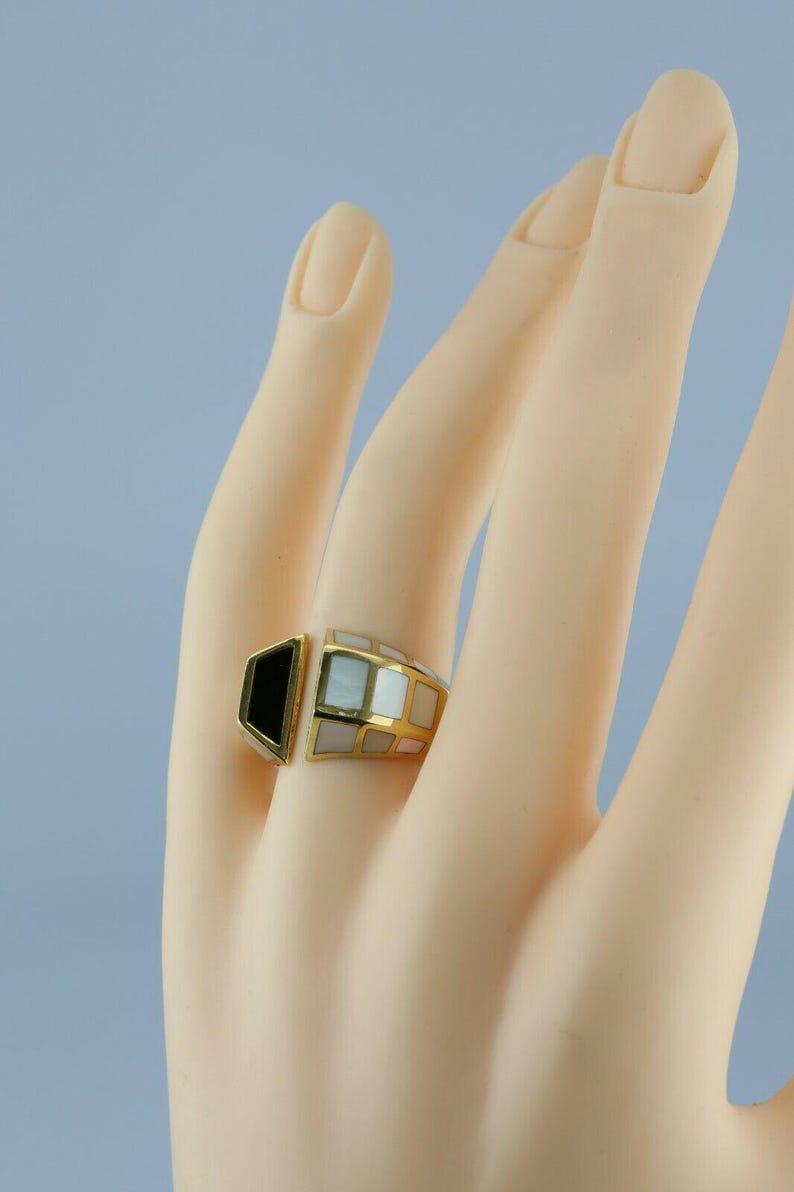 May include: A gold ring with black and white inlay. The ring is geometric in shape and has a unique design.