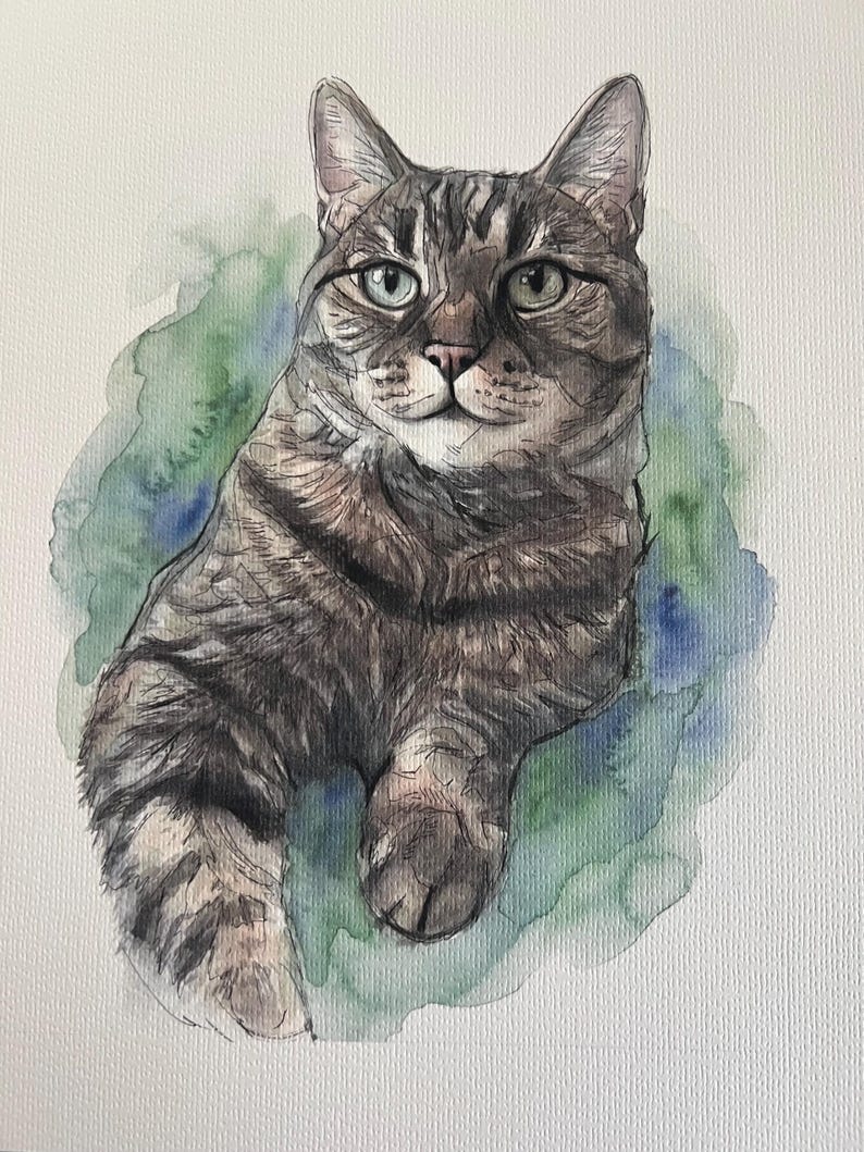 Puede incluir: Una pintura a la acuarela de un gato atigrado marr&oacute;n y gris con rayas oscuras y ojos de color verde claro. El gato aparece en posici&oacute;n sentada sobre un fondo suave y difuminado de aguadas de color verde y azul sobre papel texturizado.