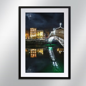 May include: A night-time view of a white bridge spanning a river in Dublin, Ireland. The bridge is illuminated with lights, and the reflections of the lights can be seen in the water. The buildings on the opposite side of the river are also lit up.