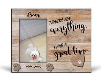 May include: A wooden photo frame with a brown woodgrain pattern. The frame has a photo of a white dog with the name "Bear" and the dates "1996-2009" printed below the photo. The text "Thanks for everything. I had a great time." is printed on the right side of the frame with a brown heart with a paw print in the center.
