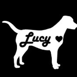 May include: A white silhouette of a dog with the name "Lucy" in cursive script and a heart symbol. The dog is standing on all fours against a black background. The tail is curved upwards.