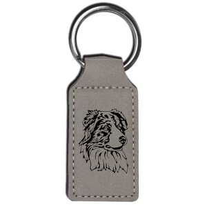 May include: Gray leather keychain with a black silhouette of an Australian Shepherd dog's head.