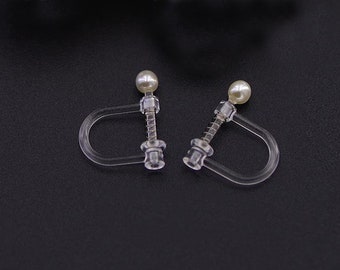 May include: A pair of clear plastic clip-on earrings with a pearl-like bead on each earring.