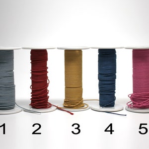 May include: Five spools of elastic cord in different colors: light blue, red, yellow, dark blue, and pink. The spools are labeled 1 through 5.
