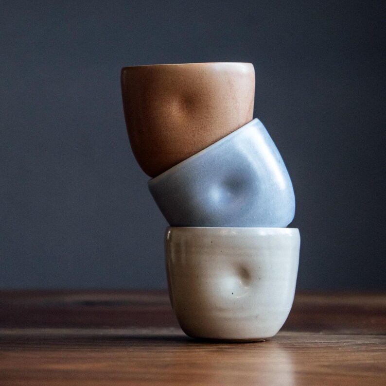Pu&ograve; includere: Tre tazze in ceramica impilate l'una sull'altra. La tazza superiore &egrave; di colore marrone chiaro, la tazza centrale &egrave; di colore blu chiaro e la tazza inferiore &egrave; di colore bianco. Tutte e tre le tazze hanno una superficie testurizzata e irregolare.