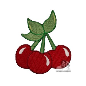 Può includere: Una toppa ricamata raffigurante tre ciliegie rosso vivo con riflessi bianchi e due foglie verdi su steli verdi. Il disegno è cucito con una trama di filo visibile e include una piccola filigrana nell'angolo in basso a destra.