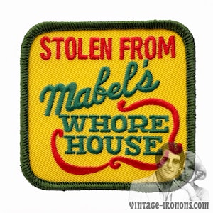 May include: A yellow square patch with green stitching around the edges. The patch has red text that says "Stolen From Mabel's Whore House". The text "Mabel's" is in green cursive lettering.
