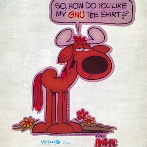 May include: A cartoon moose with a speech bubble that says "SO, HOW DO YOU LIKE MY GNU TEE SHIRT?" The moose is brown with a red tail and is standing on a green patch of grass with flowers. The text "GNU ANIMAL CRACKERS" is at the bottom of the image.