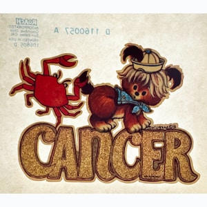 May include: A vintage iron-on patch featuring a cartoon crab and a dog with a sailor hat. The patch is gold with the word "Cancer" in large letters.