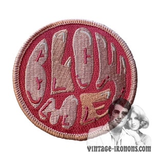 Könnte beinhalten: Ein gestickter Bügeleisen-Aufnäher in Rosa und Beige mit dem Text "Blow Me" in einer Retro-Schrift.