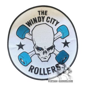 May include: Embroidered patch with a white background, featuring a skull with crossed roller skates in turquoise and black stars. The text "THE WINDY CITY ROLLERS" is arched around the design. The patch has a black border.