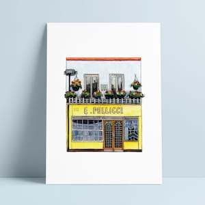 Op de afbeelding: Waterverfillustratie van een gebouw met een gele gevel en de tekst "E. Pellicci". Het gebouw heeft ramen, hangende bloembakken en een rode rand. Het kunstwerk staat op een witte achtergrond.