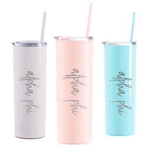 May include: Three stainless steel tumblers with lids and straws. The tumblers are in light gray, light pink, and light blue. Each tumbler has the text "alpha phi" printed on the side.
