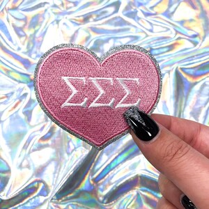 May include: Pink heart-shaped patch with silver glitter trim and white embroidered letters spelling "ZZZ"