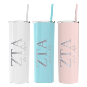 May include: Three stainless steel tumblers with straws. The tumblers are white, light blue, and pink. Each tumbler has the letters "ZTA" and the words "Zeta Tau Alpha" in silver lettering.