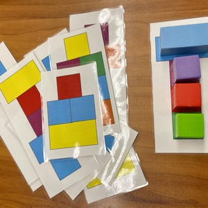 May include: A set of cards with different colored squares arranged in various patterns. The cards are designed to help children learn about colors, shapes, and patterns.