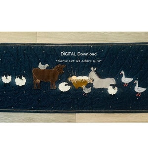 May include: A digital download of a quilted wall hanging featuring a nativity scene with a cow, donkey, sheep, and geese. The background is a dark blue fabric with gold glitter stars. The text "DIGITAL Download" and "Come Let Us Adore Him" is printed on the wall hanging.