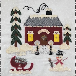 May include: A felt appliqué Christmas scene with a red house with a welcome sign, two trees, a snowman holding a star, and a red sled with a Christmas tree inside. The background is white with a dotted pattern.