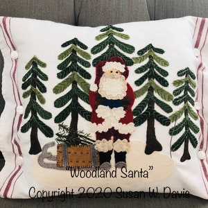 May include: White pillow with a red and white Santa Claus figure standing in a snowy forest with green trees. The pillow has a red and white striped border and the text "Woodland Santa" and "Copyright 2020 Susan W. Davis".