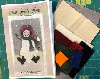 May include: A craft kit for making a felt snowman applique. The kit includes a pattern, instructions, and various colours of felt fabric. The pattern is titled "Aunt Susie's House W203 "Snow Buddy"".