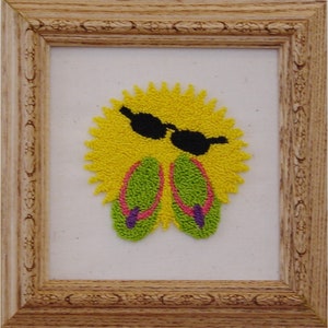 May include: Framed artwork featuring a yellow sun with black sunglasses and green flip-flops with purple accents. The artwork is framed in a light brown, ornate wooden frame, perfect for summer decor.
