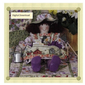 May include: A digital download pattern for a doll dressed in a floral print dress and a purple hat. The doll is holding gardening tools and sitting on a floral patterned quilt. The text "Digital Download" is displayed in the top left corner of the image.