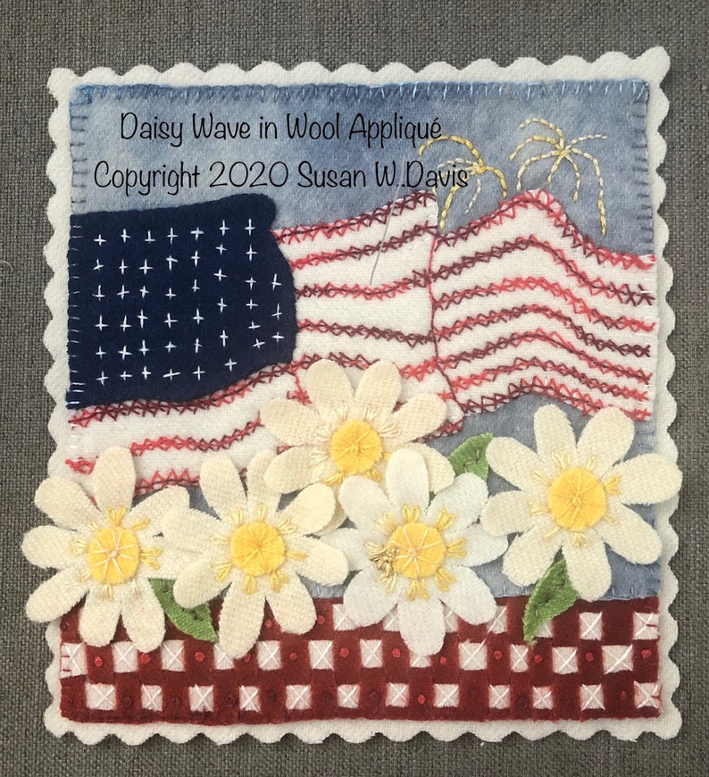May include: A wool applique artwork featuring a red, white, and blue American flag with a wave design. The flag is surrounded by white daisies with yellow centers. The background is a red and white gingham pattern. The artwork is titled "Daisy Wave in Wool Applique" and is copyrighted 2020 by Susan W. Davis.