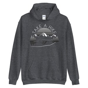 Puede incluir: Una sudadera con capucha gris oscuro con el texto "TAKE A HIKE" en letras blancas, una cordillera y un gr&aacute;fico de puesta de sol.