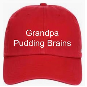 May include: A bright red baseball cap featuring the white text Grandpa Pudding Brains printed across the front center. The cap has a structured crown, a curved brim, and a button at the top, providing a classic look with bold, clear lettering.